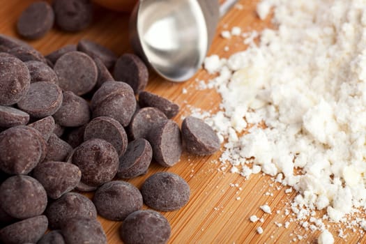 Chocolate chips, flour and a measuring spoon ready for making cookies.