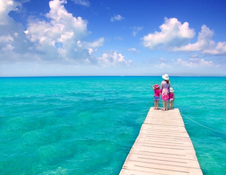 Daughters and mother in jetty on Formentera with turquoise sea