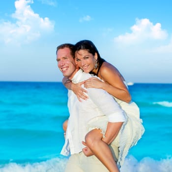 couple in love piggyback playing in a beach at blue Mediterranean