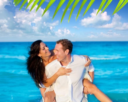 couple in love piggyback playing in a beach at blue Mediterranean