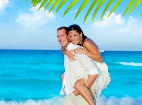 couple in love piggyback playing in a beach at blue Mediterranean