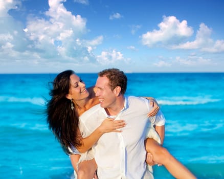 couple in love piggyback playing in a beach at blue Mediterranean