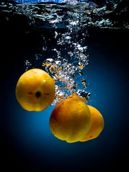 Fresh apricot in water on a black/blue background with air bubbles