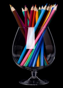 Colorful pencils in a glass on a black background