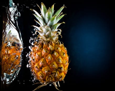 Fresh pineapple in water on a black/blue background with air bubbles