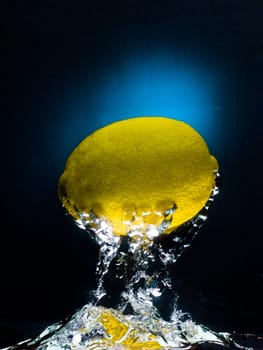 Fresh lemon in water on a black/blue background with air bubbles