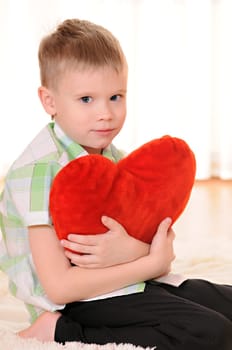 the child sit on the floor with a red plush heart