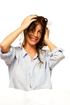 Happy woman in pajamas playing with her hair against white background