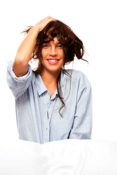 Happy woman in pajamas holding her hair against white background