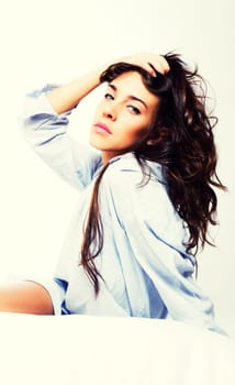 Beautiful woman in bed holding her hair against white background