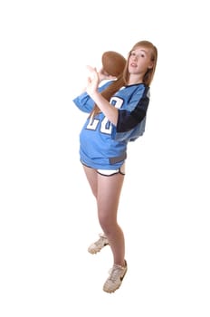 A young girl in a blue football outfit standing in the studio and show how to play football, for white background.