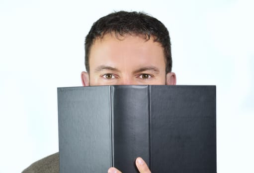 Handsome young man behind a big book, isolated on white