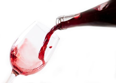 Red wine pouring into glass, isolated on white background