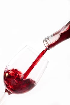 Red wine pouring into glass, isolated on white background