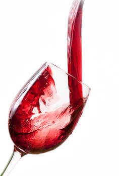 Red wine pouring into glass, isolated on white background