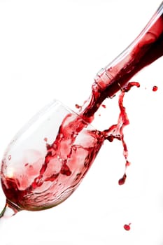 Red wine pouring into glass, isolated on white background