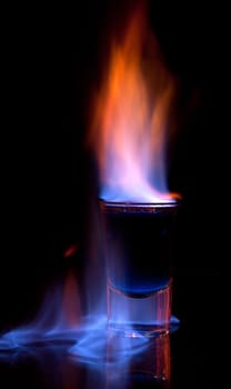 Burning drink in shot glass on a table