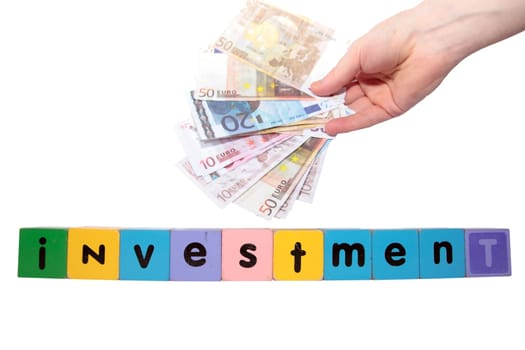 toy letters that spell house investment with cash in hand against a white background with clipping path