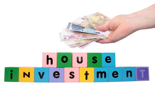 toy letters that spell house investment with cash in hand against a white background with clipping path