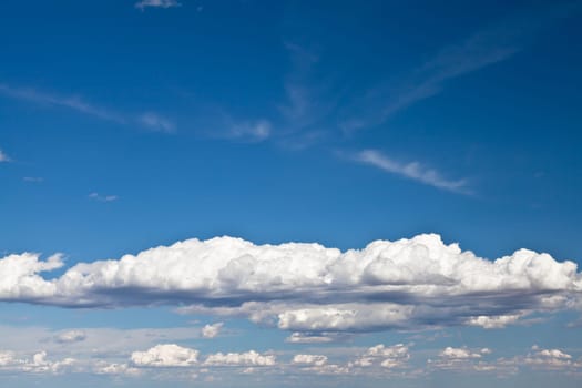 Blue summer sky with low white clouds with copy space