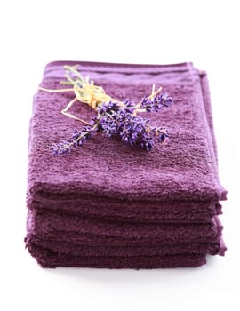 Stack of towels with lavender on white background