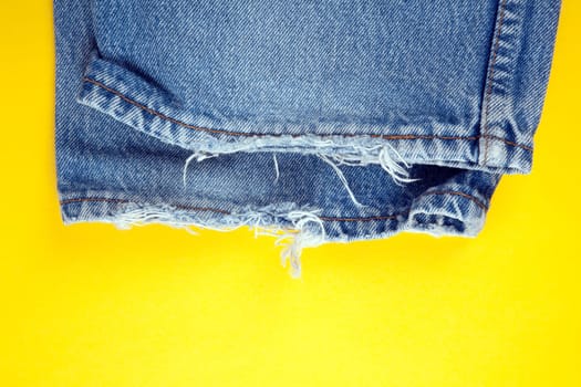 Frayed denim jeans  with yellow background