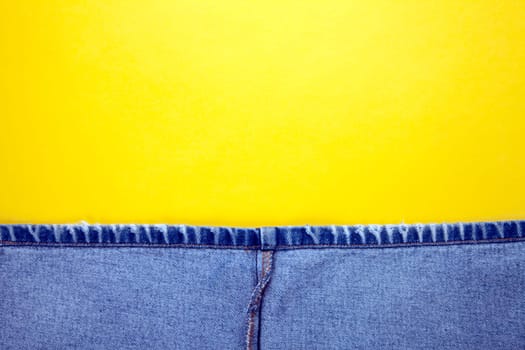Blue jeans with yellow stitches and yellow background