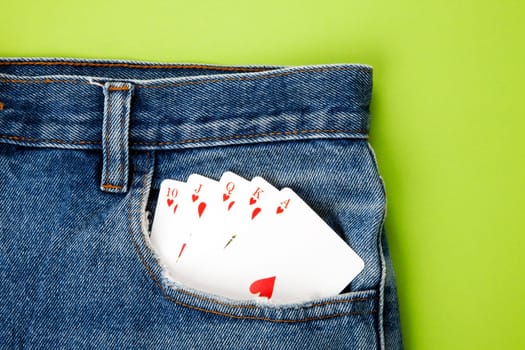 Royal flush with playing cards in blue jeans pocket with green background