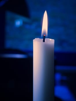 Single glowing candle against blue textured background