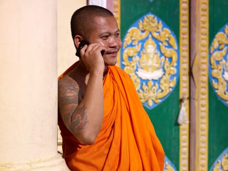 mid adult buddhist monk speaking with cell phone in monastery, Phnom Penh, Cambodia, Asia