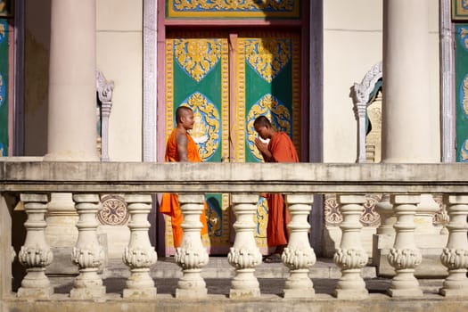 Two young buddhist monks meeting and saluting in a temple, Phnom, Penh, Cambodia, Asia. Side view