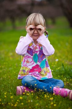 Cute little girl outdoors looking through imaginary binoculars