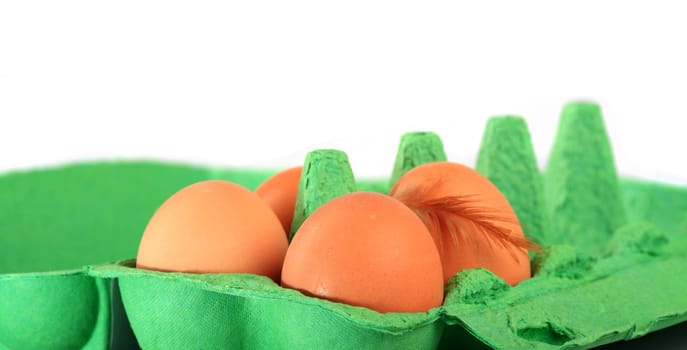 Brown chicken eggs in a cardboard box with down feather