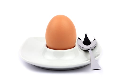 Brown egg in egg cup with spoon