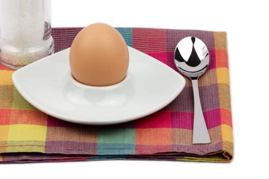 Breakfast egg in an egg cup with salt mill and spoon