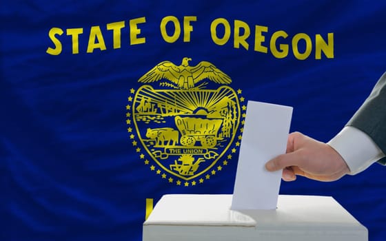 man putting ballot in a box during elections  in front of flag american state of oklahoma