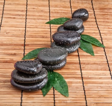 zen stones and leaves with water drops. leaf and basalt stones.