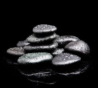 Spa Stones. black shiny zen stones with water drops over black background