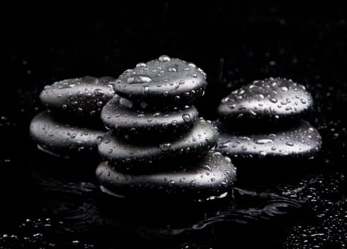 Spa Stones. black shiny zen stones with water drops over black background