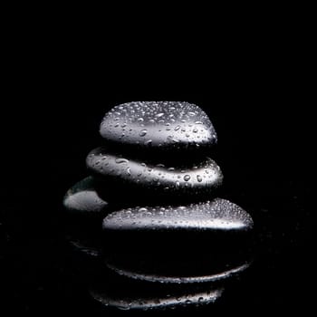 Spa Stones. black shiny zen stones with water drops over black background
