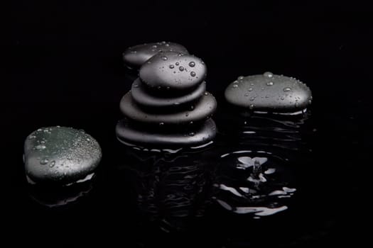 Spa Stones. black shiny zen stones with water drops over black background