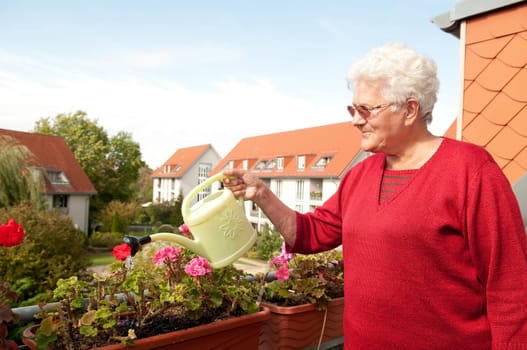 Senior woman watering flowers on the balcony