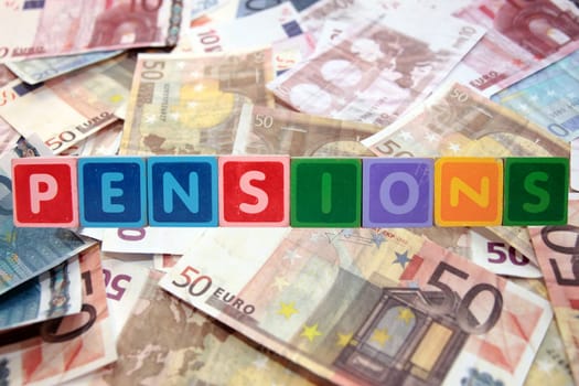 toy letters that spell pensions against a cash background with clipping path