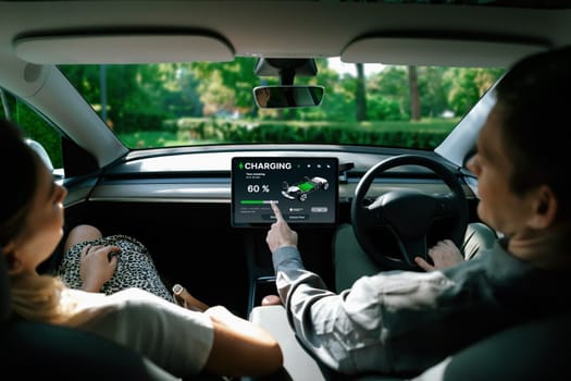 Electric car driver checks battery charging status, range and charging limit on app screen in the car. Smart technology device show EV car recharging data of electric storage in car battery innards.