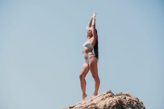 Woman meditating in yoga pose silhouette at the ocean, beach and rock mountains. Motivation and inspirational fit and exercising. Healthy lifestyle outdoors in nature, fitness concept.