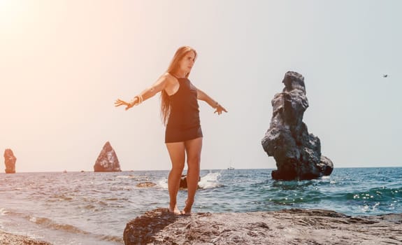 Woman travel sea. Young Happy woman in a long red dress posing on a beach near the sea on background of volcanic rocks, like in Iceland, sharing travel adventure journey