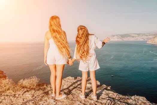 Close up portrait of mom and her teenage daughter hugging and smiling together over sunset sea view. Beautiful woman relaxing with her child.