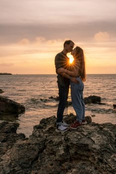 silhouettes in love romantic couple lovers hugging, kissing, touching, eye contact at sunset, sunrise on the background of the sea, the sun, the clouds in fiery red, orange colors.