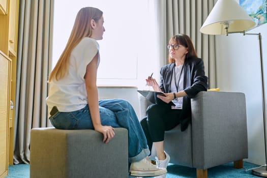 Female psychologist therapist working with young teen girl sitting in office. Teenage female student at therapy meeting with counselor. Psychology therapy psychotherapy youth mental health treatment