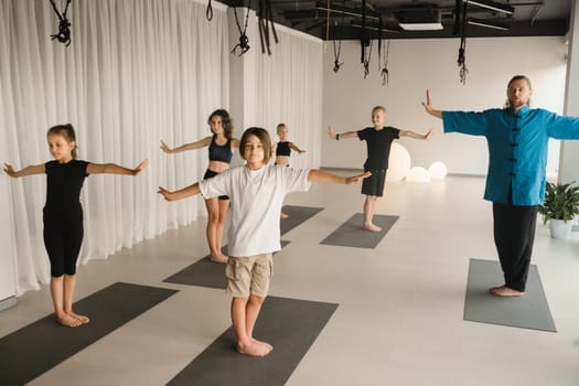 Children do yoga in the gym under the guidance of an instructor. Children's gymnastics.